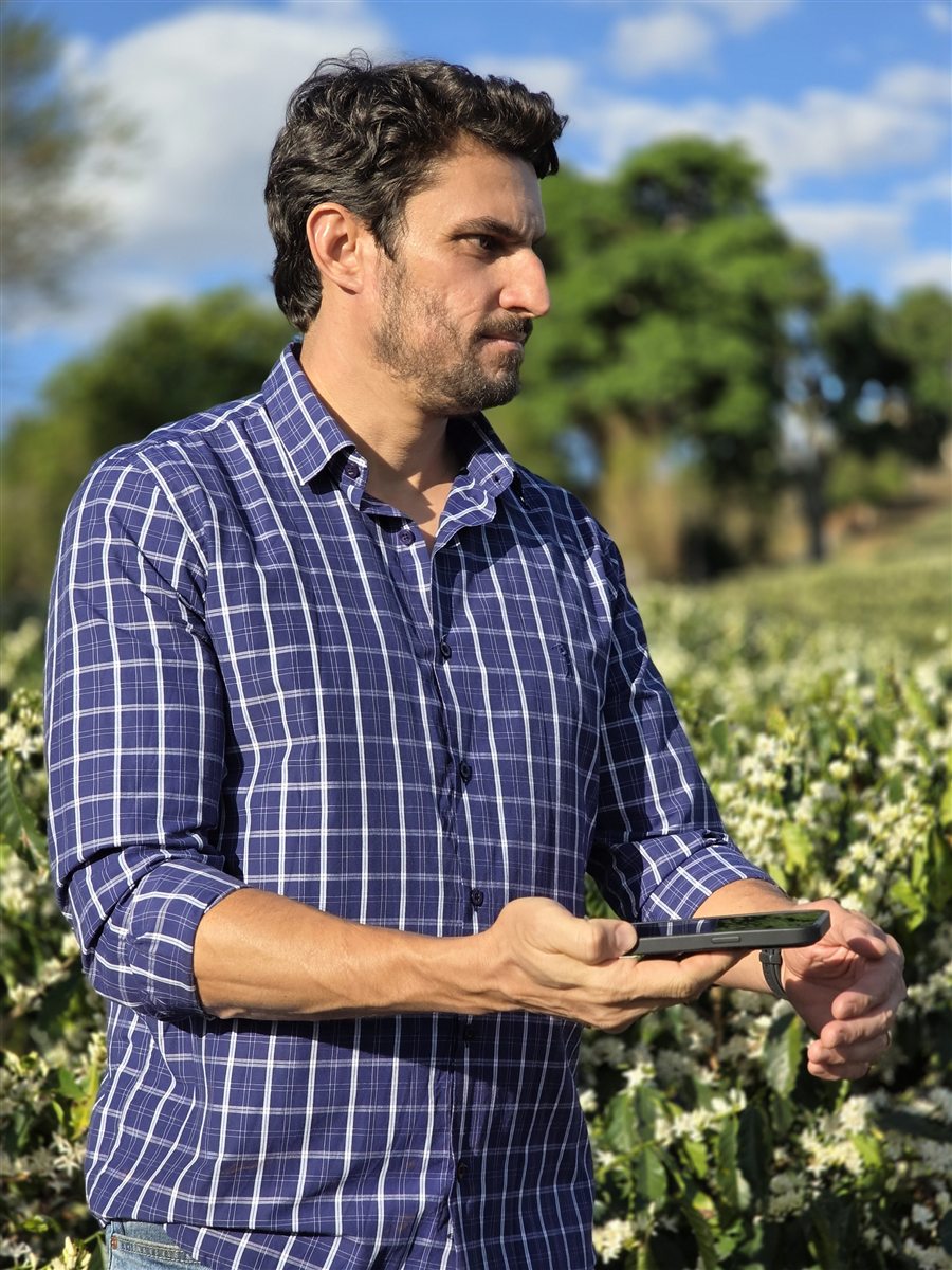 F&aacute;bio Kinsch no cafezal, consultando o assistente no celular